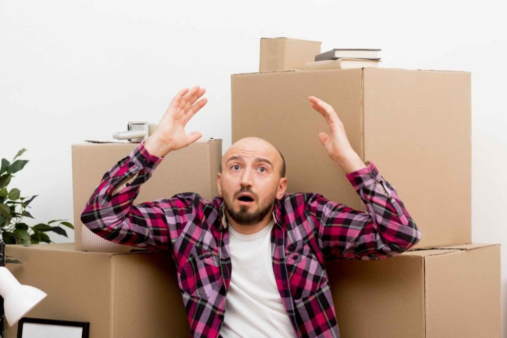 Man looking stressed surrounded by moving boxes, highlighting the challenges of choosing the wrong packers and movers.